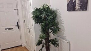 A hallway with a potted plant, a white door, and a radiator. - NightRest Homes 6 Bedroom Short & Long Term Smart Tv in each Room, Free Parking  (Oxley Park)