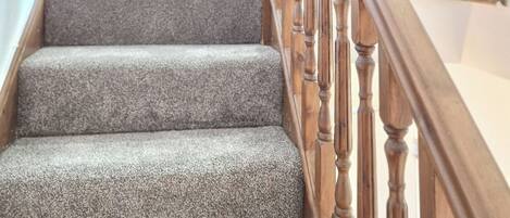 A staircase with wooden balusters and carpeted steps leading to an upper floor.