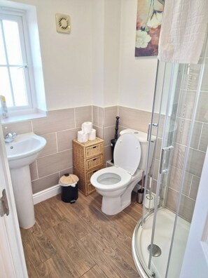 A bathroom with a toilet, bidet, sink, and a glass shower enclosure.