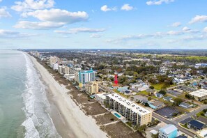 A coastal cityscape with a beachfront hotel, residential buildings, and a clear sky.