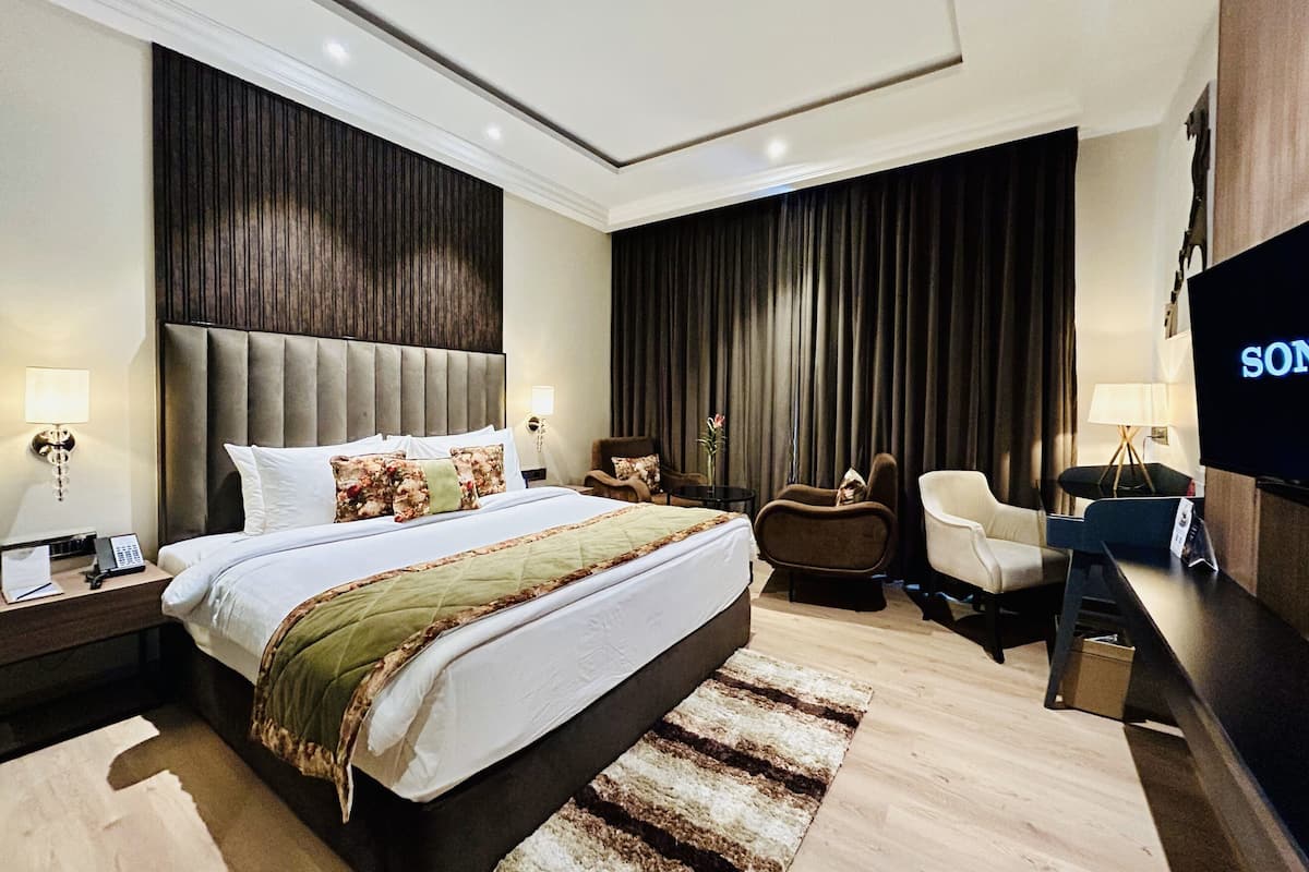 A modern hotel bedroom with a large bed, a TV, a desk, and a chair.