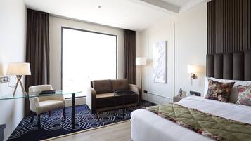 Ein Hotelzimmer mit Bett, Sofa, Glastisch und Schreibtisch.