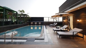 A rooftop pool area with lounge chairs and a small table, surrounded by a wooden wall and a metal railing. - Fortune Ranjit Vihar, Amritsar - Member ITC Hotels' Group (Amritsar)