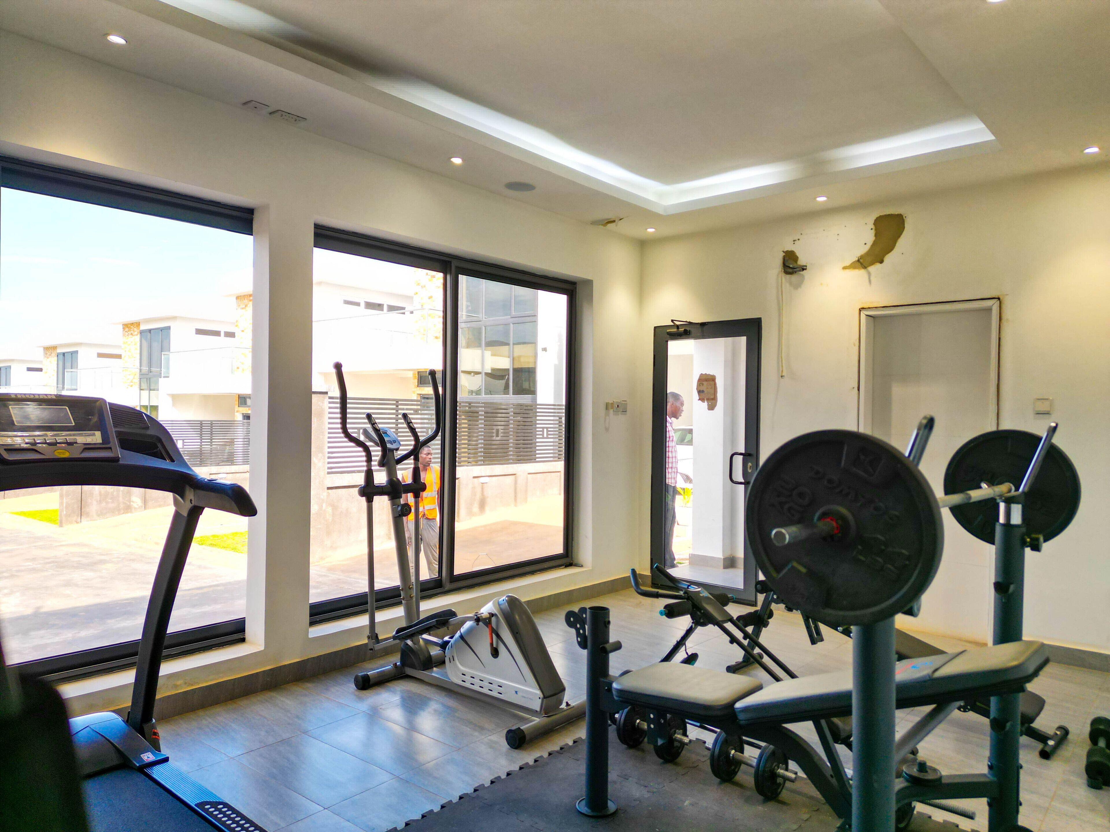 A gym with cardio equipment, weight machines, and a large window offering a view of the outside.