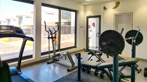Ein Fitnessstudio mit Cardiogeräten, Krafttrainingsmaschinen und einem großen Fenster mit Blick nach draußen.
