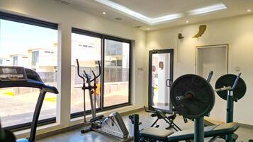 A gym with cardio equipment, weight machines, and a large window offering a view of the outside.