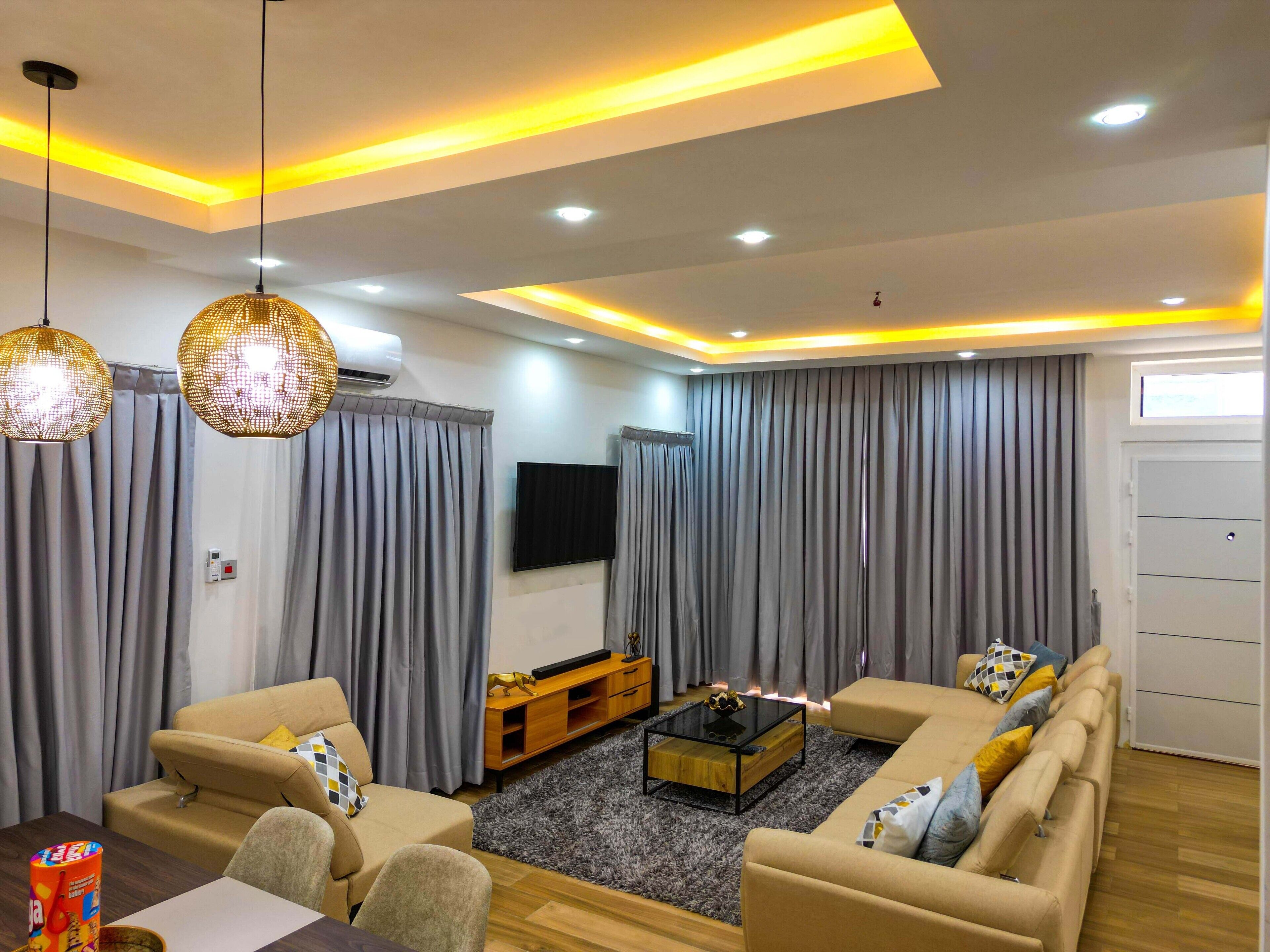A modern living room with a sofa set, a coffee table, and a flat-screen TV.