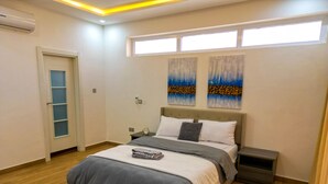 Ein modernes Schlafzimmer mit Bett, Nachttischen, Fenster und Wandkunst.