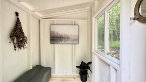 Una habitación acogedora con un banco de madera, un cuadro con una imagen de un lago y una planta en maceta.
