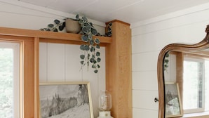 Un baño con estantes de madera, un espejo y un cuadro enmarcado.