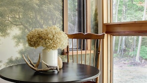 Una mesa de comedor con un jarrón de flores, una silla y una lámpara.