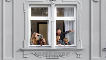 Una finestra con cornice decorativa, attraverso cui si vedono alcune persone.