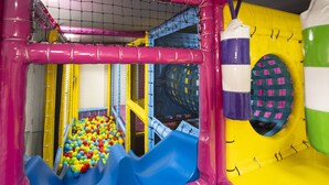 A colorful indoor play area with a ball pit, slides, and a punching bag.