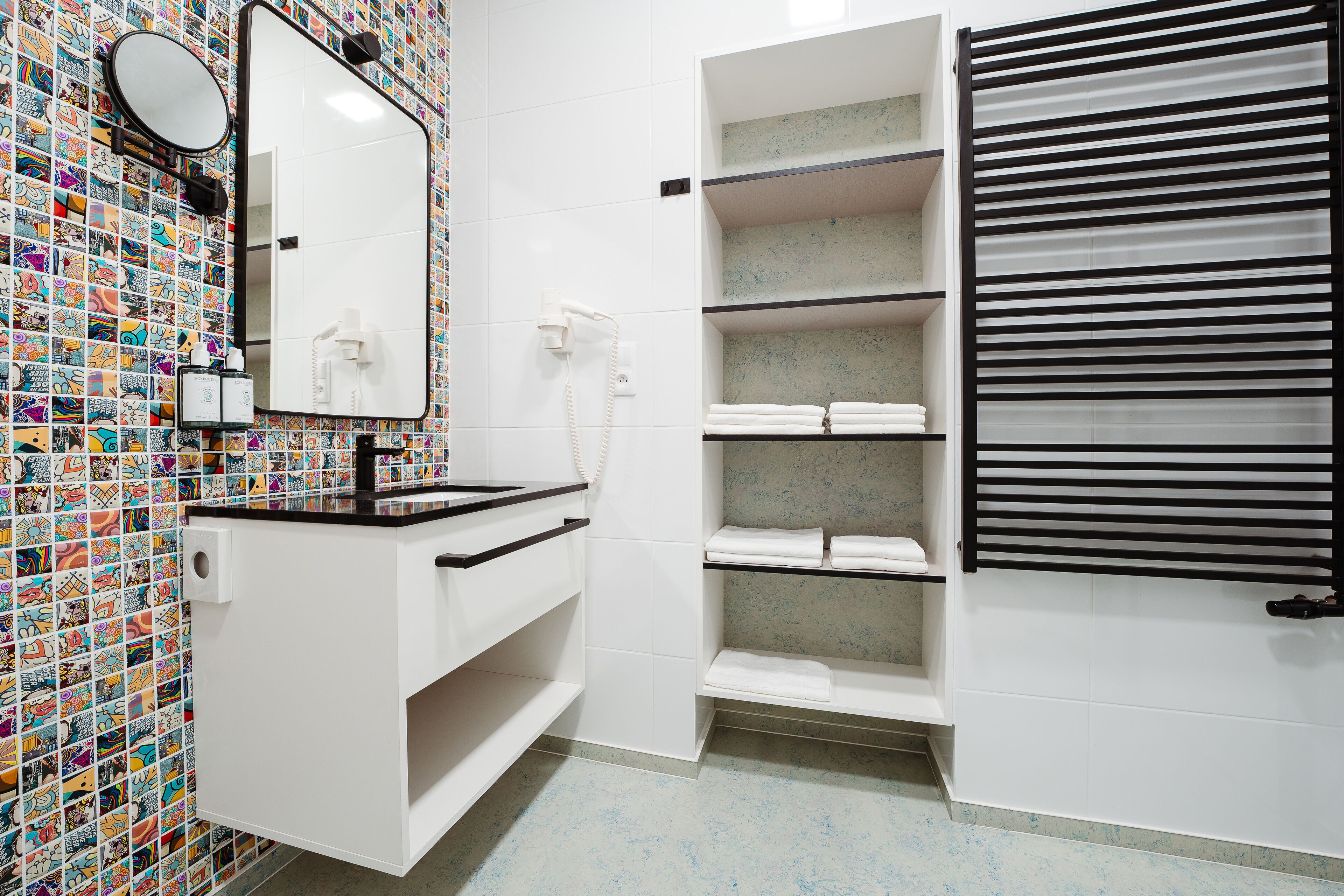 A bathroom with a tiled wall, a white sink with a mirror, a towel rack, and a toilet.