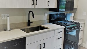 A modern kitchen with white cabinetry, a black stove, and a built-in microwave. - Outlaw Inn Unit 3. MODERN, newly remodeled unit, STEPS from Main Street!
 (Ouray)