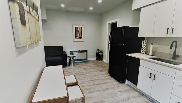 A modern kitchen with white cabinets and a black refrigerator. There is a dining area with a wooden table and chairs. - Outlaw Inn Unit 3. MODERN, newly remodeled unit, STEPS from Main Street!
 (Ouray)