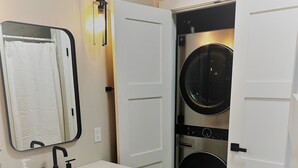 A compact bathroom with a sink, mirror, and a wall-mounted light fixture. - Outlaw Inn Unit 3. MODERN, newly remodeled unit, STEPS from Main Street!
 (Ouray)