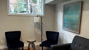 A living room with a cowhide rug, two dark armchairs, a grey sofa, a floor lamp, and a large window with a city view. - Outlaw Inn Unit 3. MODERN, newly remodeled unit, STEPS from Main Street!
 (Ouray)