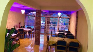 A restaurant with a dining area featuring tables and chairs, a brick pillar, and a decorative metal gate. - Odo So Royal Hotel (Akosombo)