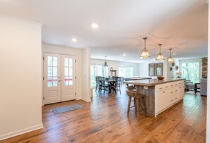 A spacious kitchen with hardwood floors, a central island, pendant lighting, and a dining area with chairs and a table. - Eden Isle Getaway with Pool Table Near Red Apple Inn (Heber Springs)