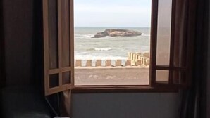 Una habitación con un amplio ventanal con vista a la playa.