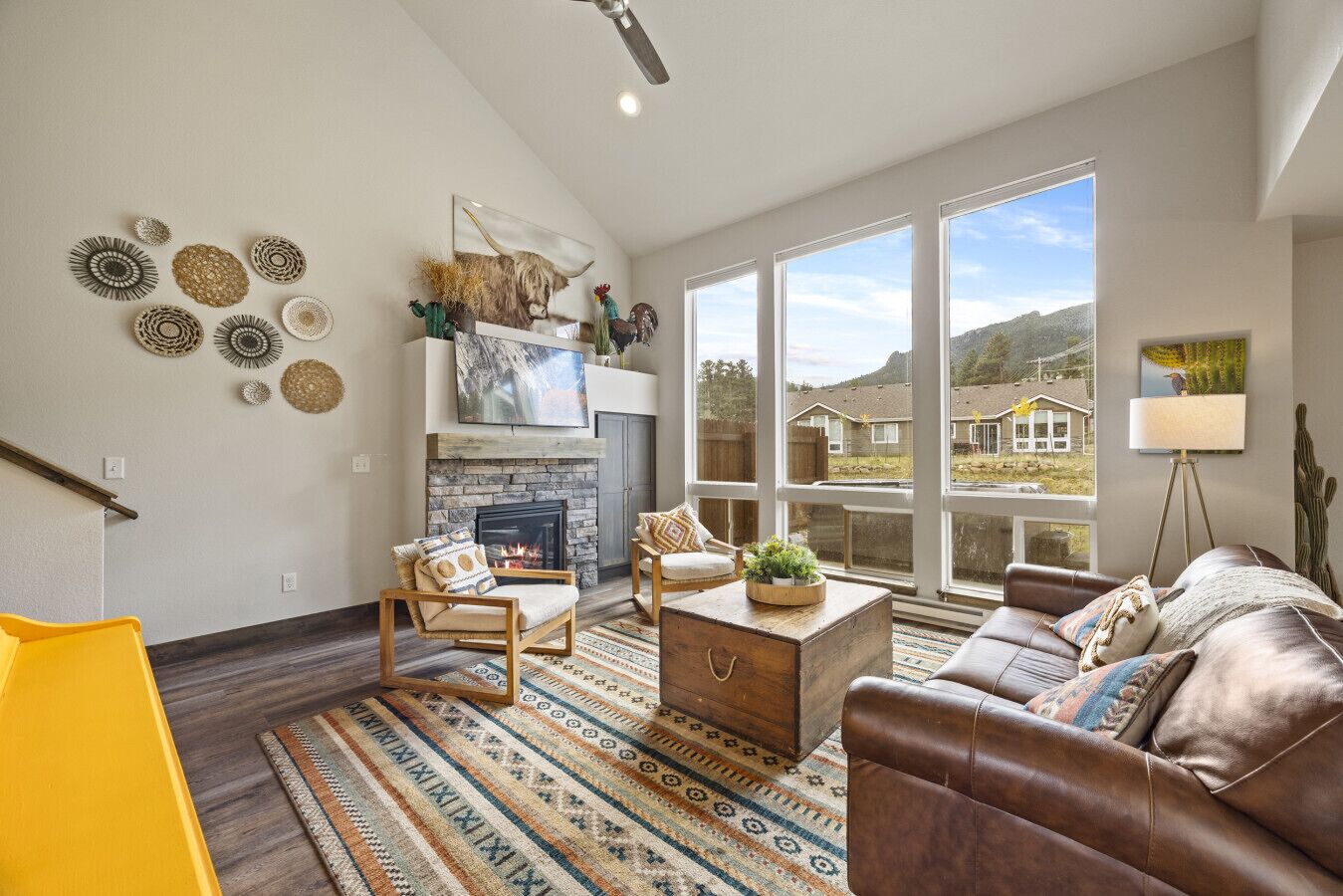 A spacious living room with a fireplace, large windows, and a variety of decorative items on the walls.
