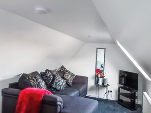 A modern living room with a sofa, a TV, and a mirror.