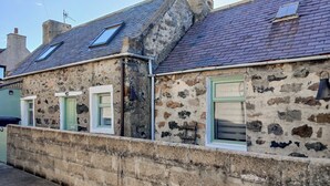 A stone building with a sloped roof, multiple windows, and a chimney. - 3 bedroom accommodation in Fraserburgh (Fraserburgh)