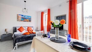 A modern hotel room with a bed, a dining table, and a view of the city. - Modern Studio, Central Location (Gzira)