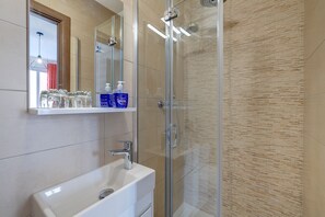 A modern bathroom with a glass shower enclosure, a white sink, and a mirror above the sink. - Modern Studio, Central Location (Gzira)