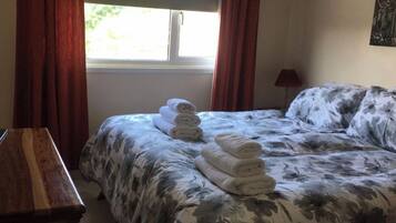 Ein Schlafzimmer mit einem Bett, einem Nachttisch aus Holz und einem Fenster mit Vorhängen.
