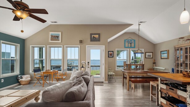 A spacious living area with a large sofa, dining table, and kitchen area. -  WATERFRONT Property on KDH Bike Path with water access, bikes, kayak, and canoe (Kill Devil Hills)