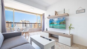 Una sala de estar moderna con un televisor grande, un sofá, una mesa de centro y un comedor con sillas.