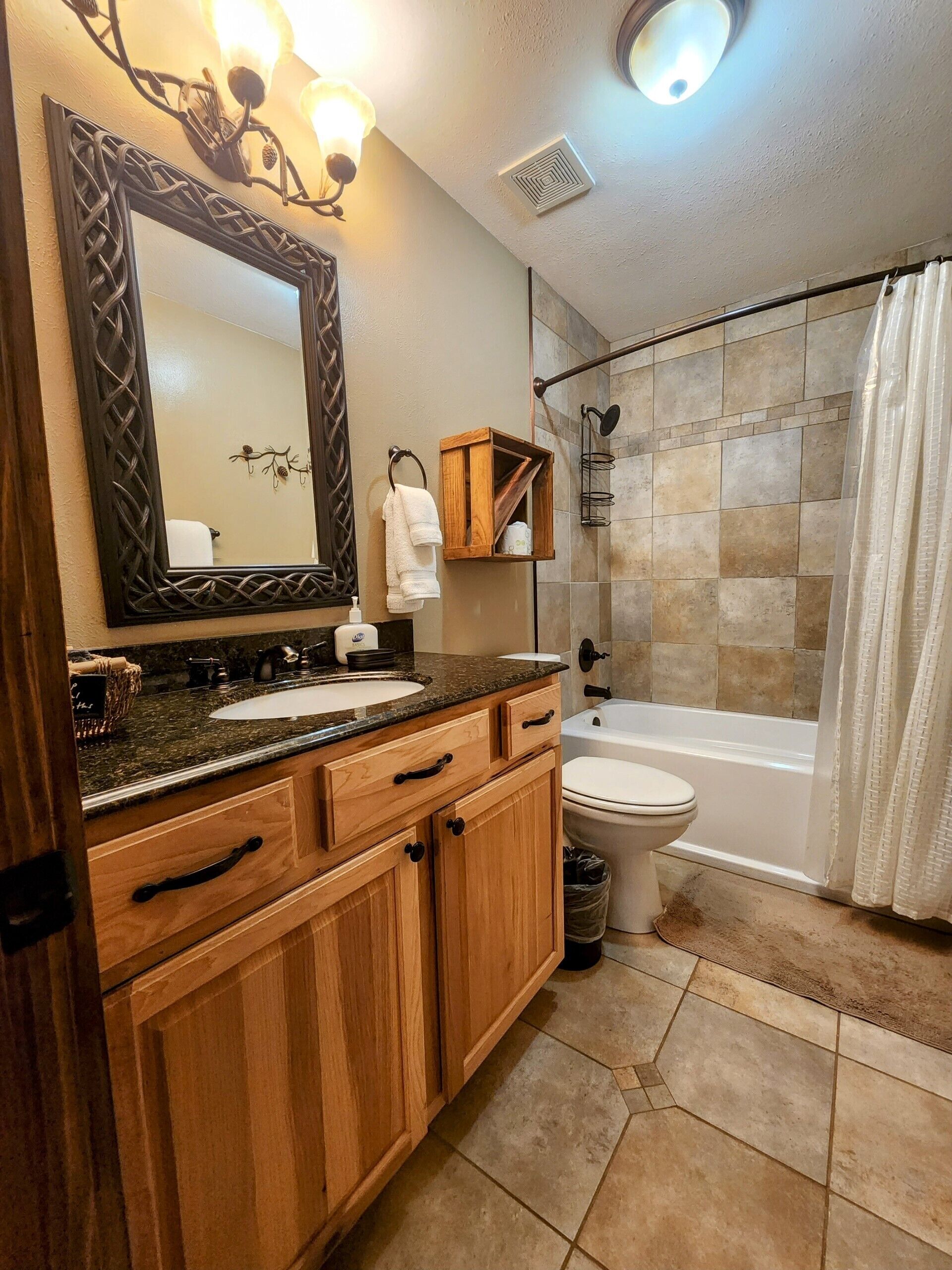 Une salle de bain avec un meuble-lavabo en bois, un grand miroir, un lavabo, des toilettes et un espace douche.