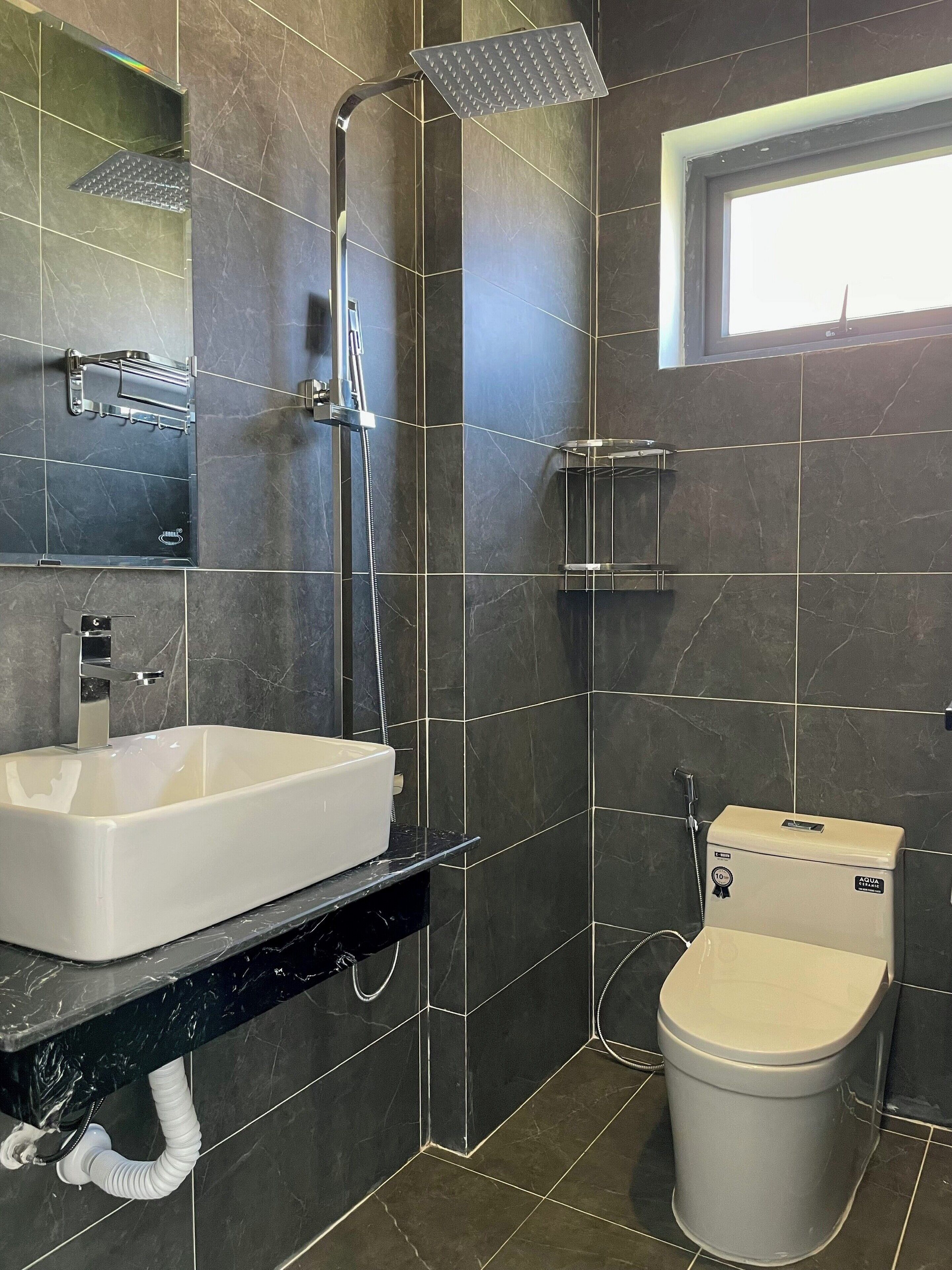 A modern bathroom with a white sink, a shower with a handheld showerhead, a toilet, and a towel rack.