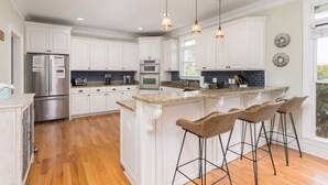 Une cuisine moderne avec des meubles blancs, un plan de travail en granit et un îlot central doté de tabourets de bar.