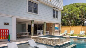 Un jardin avec une piscine, des chaises longues, une terrasse en bois et une clôture en bois.