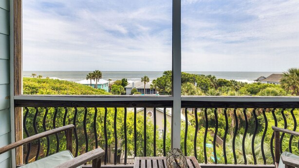 Un balcon offrant une vue sur l’océan et une végétation luxuriante.
