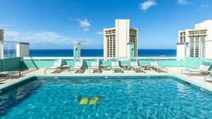 A pool area with lounge chairs and a view of the ocean. - Modern Pacific Monarch 1-Bedroom | Rooftop Pool (Honolulu)