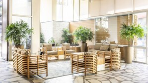 A spacious indoor area with wooden furniture and large potted plants. - Modern Pacific Monarch 1-Bedroom | Rooftop Pool (Honolulu)
