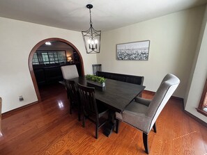 A dining area with a dark wooden table, four chairs, a chandelier, and a framed picture on the wall.