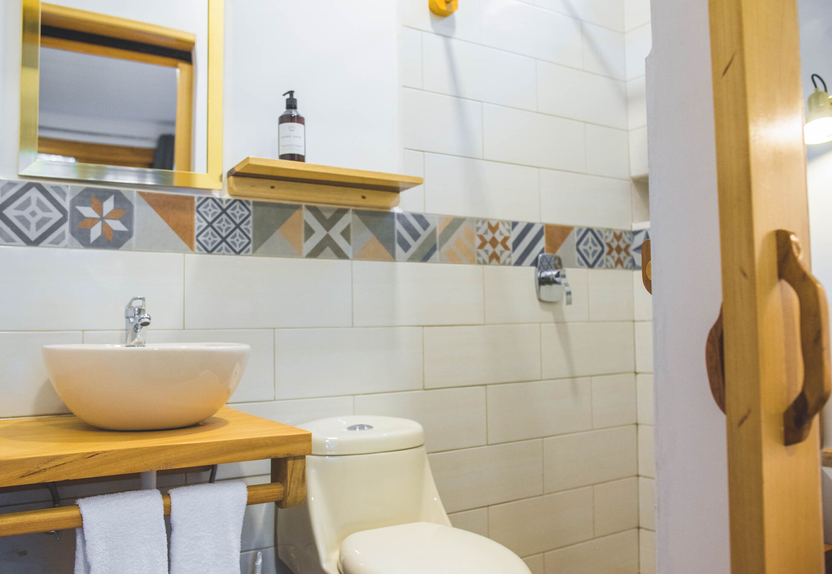 Een badkamer met een witte wastafel, toilet en een houten wastafelmeubel.