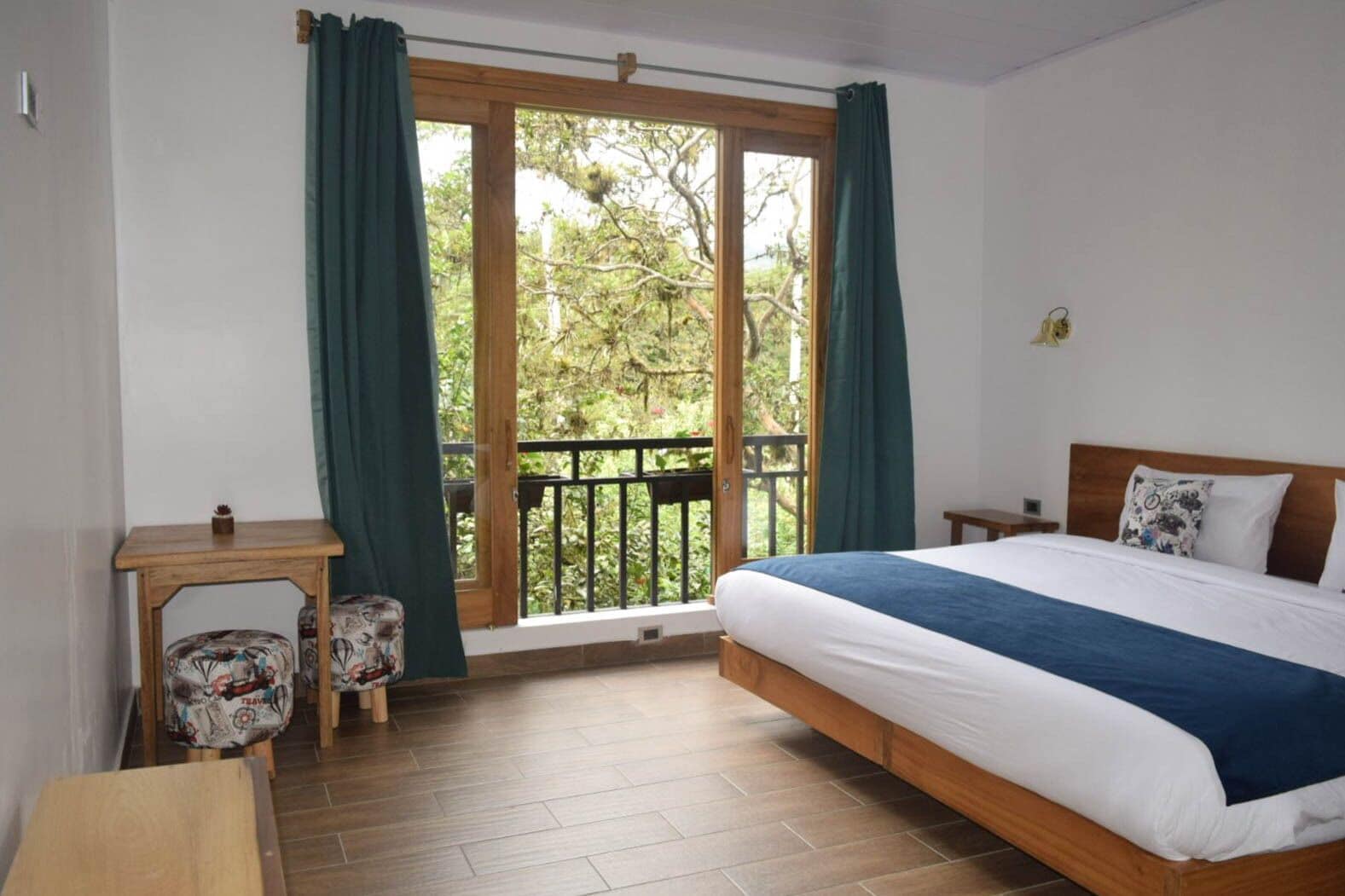 Un dormitorio con una cama grande, una mesita, una silla y vistas a un balcón exterior a través de puertas corredizas de vidrio.