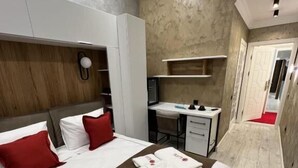 A hotel room with a bed, a desk, and a wardrobe. - E-Lite (Astana)