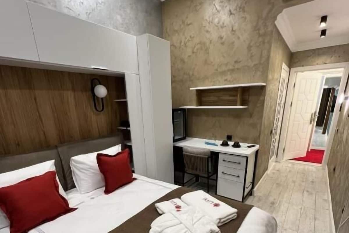 A hotel room with a bed, a desk, and a wardrobe.