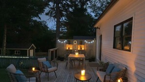 Een terras buiten met een houten dek, een tafel met stoelen en kaarsen die sfeerverlichting geven.