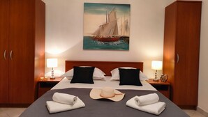 Ein Hotelzimmer mit einem Bett, zwei Nachttischen, einem Segelboot-Bild und Holzschränken.