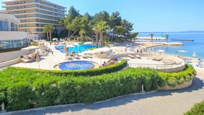 Ein Resort mit großem Pool, Liegestühlen und Meerblick.