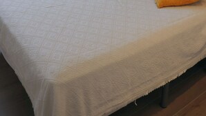 A bedroom with a bed, a ceiling fan, a nightstand, and a wall-mounted lamp. - Apartamento Golden Star (Jávea)