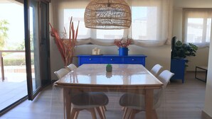 A dining area with a large table, chairs, a blue cabinet, and a hanging light fixture. - Apartamento Golden Star (Jávea)